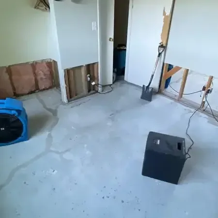 Air movers and a dehumidifier in a room with the lower drywall cut away