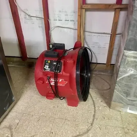 Air movers and a dehumidifier drying a room after a slab leak