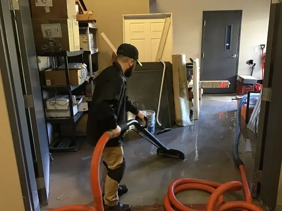 Technician pulling standing water off a floor with an extraction wand